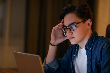 Concentrated young man IT employee overworking at office, using laptopの写真素材