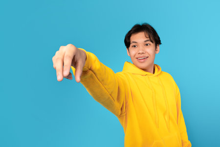 Asian Teenager Boy Holding In Hand Invisible Object, Blue Backgroundの写真素材