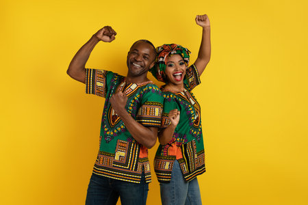 Excited happy black lovers celebrating success on yellow, gesturingの写真素材