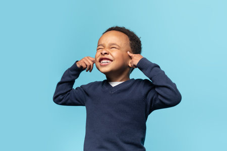 Funny black boy touchig his temples and closing eyes, kid trying to remember some information, blue backgroundの写真素材