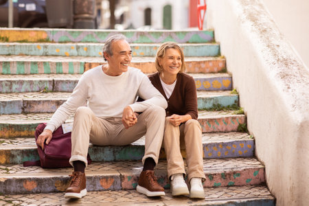 Happy Senior Tourists Couple Sitting On Colorful Steps Outdoorsの写真素材