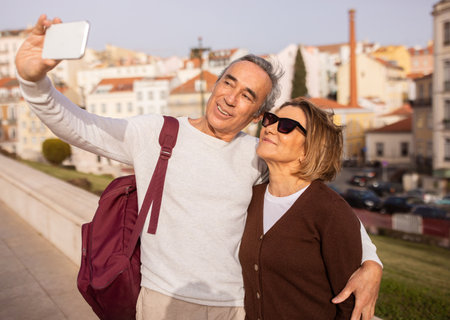 Happy Senior Tourists Couple Making Selfie On Phone Standing Outdoors