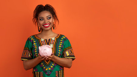 Black woman in african costume holding piggy bank, copy spaceの写真素材