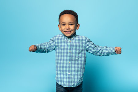 Portrait of adorable african american boy in casual clothes smiling at camera, standing over studio wall, free spaceの写真素材