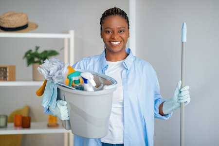 Friendly african american lady maid ready for cleaning houseの写真素材