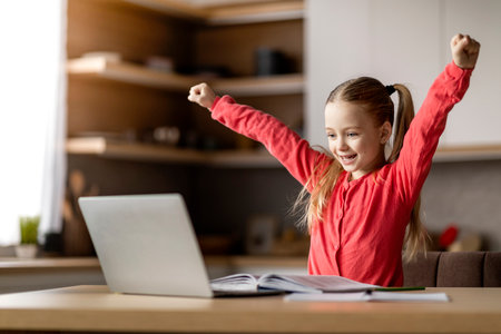 Cute Preteen Girl Celebrating Educational Success With Laptop At Homeの写真素材