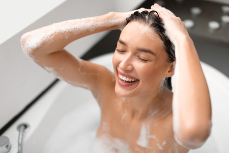 Happy Woman Applying Shampoo Washing Head Taking Bath In Bathroomの写真素材