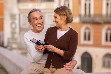 Happy Mature Couple Holding Travel Tickets And Passports Sitting Outdoorsの写真素材