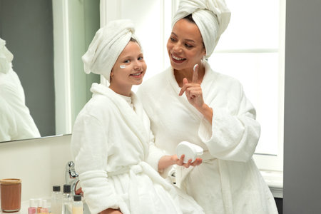 Happy european millennial woman and teen girl in bathrobes and towel have fun, take care of beauty and skinの写真素材