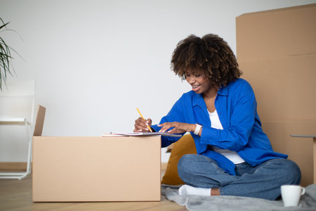 Smiling Black Female Moving Home, Writing Checklist Of Necessities For New Houseの写真素材