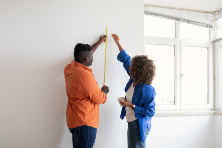 Home Repairing. Happy African American Couple Measuring Wall With Tape Rulerの写真素材