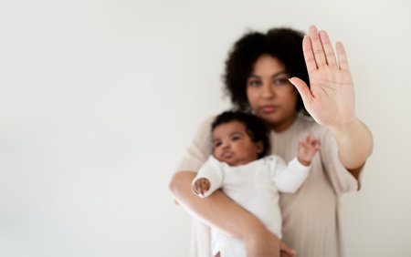 Serious confident young african american lady hold baby in arms, making stop gesture with handの写真素材