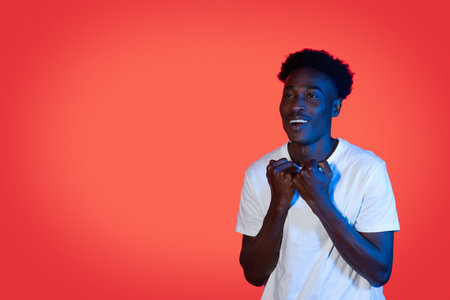 Hopeful black guy holding fists next to chest, copy spaceの写真素材