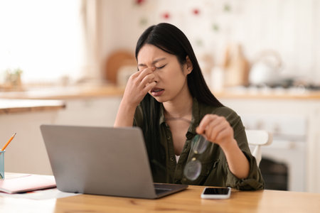 Overworked asian woman independent contractor sitting in front of laptopの写真素材