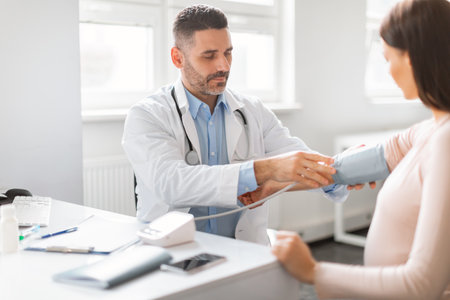 Gynecologist doctor measuring arterial blood pressure of sick pregnant lady, feeling unwell during checkup in clinicの写真素材