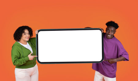 Positive mixed race couple holding big cell phone, mockupの写真素材