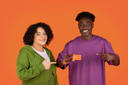 Happy multicultural lovers showing bank card, red background