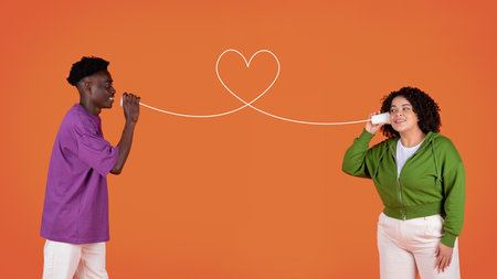 Young multiracial couple with can phone on red backgroundの写真素材