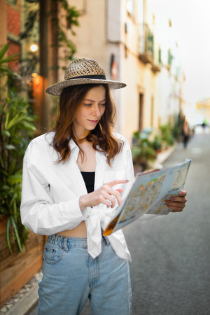 Serious pretty young caucasian female in casual and hat looking at map, enjoy trip in new city, search hotel, outsideの写真素材