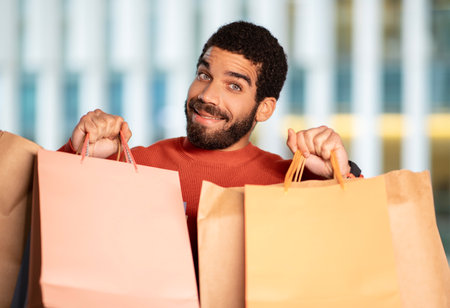 Cheerful Middle Eastern Man Shopping Posing With Shopper Bags Outdoorsの写真素材