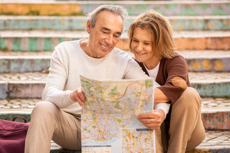 Happy Senior Couple Planning Vacation Holding Touristic Map Sitting Outsideの写真素材