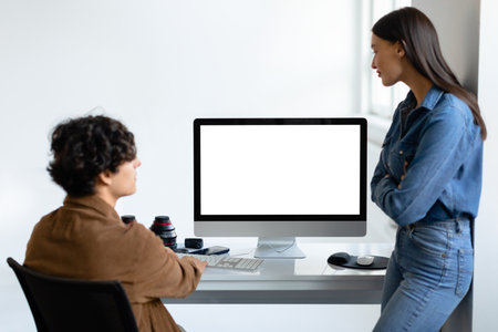 Professional male photographer and female assistant or art director discussing photos on computer...