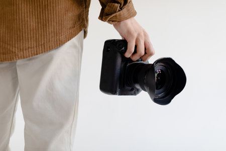 Photographer standing ready to work, holding modern camera in hand, closeup cropped shotの写真素材