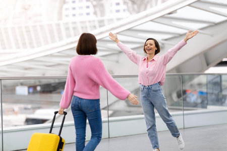 Beautiful Young Woman Meeting Her Female Friend In Airport After Arrivalの写真素材