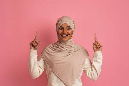 Excited Young Muslim Female In Hijab Pointing Up At Copy Spaceの写真素材