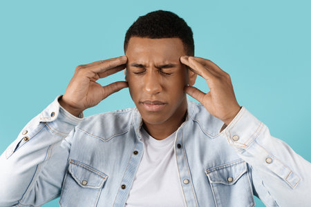 Sad millennial black guy with closed eyes suffering from headache and stress, thinkingの写真素材