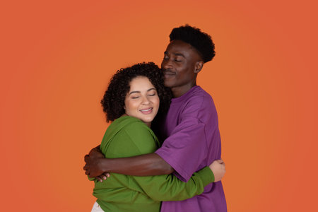 Portrait of emotional multiracial young couple bonding on redの写真素材