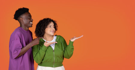 Cool millennial mixed race couple pointing at copy spaceの写真素材