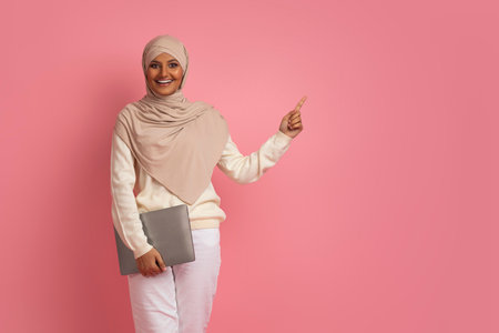 Check This. Excited Muslim Female Holding Laptop And Pointing At Copy Space