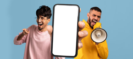 Two Arab Guys Advertising Mobile Offer, Showing Blank Smartphone And Using Megaphoneの写真素材