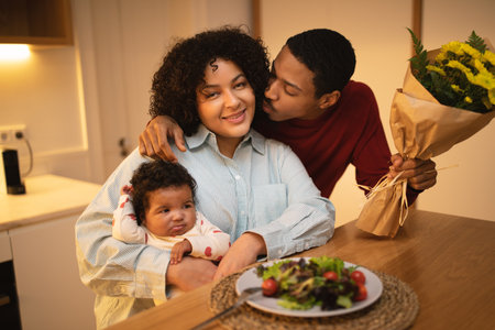 Loving black husband kissing his beautiful wife holding toddlerの写真素材