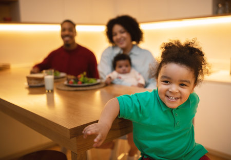 Cute black boy preschooler enjoying time with parents and siblingの写真素材