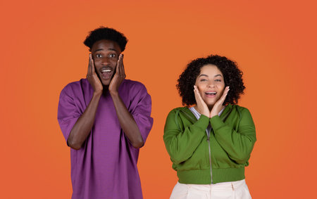 Emotional surprised multiracial couple showing amazement on red, touching facesの写真素材