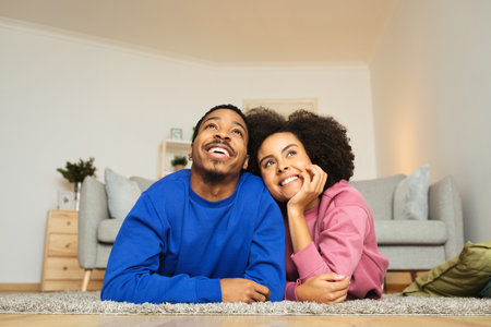 Cheerful African American Married Couple Posing Lying On Floor Indoorsの写真素材