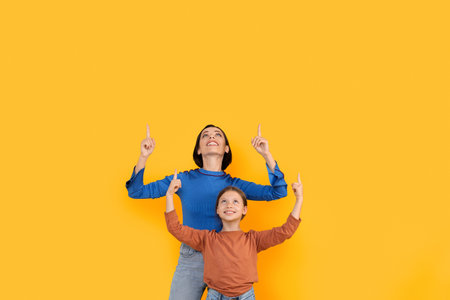 Mother And Daughter Pointing Up At Copy Space Above Their Heads