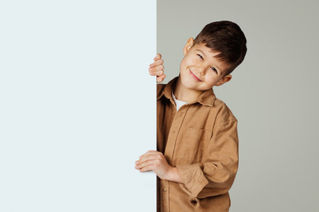 Smiling caucasian 6 years old little boy in casual with big banner with blank spaceの写真素材