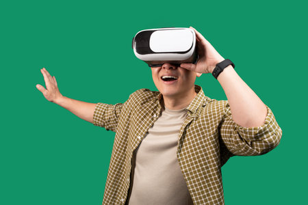 Excited asian middle aged man using VR glasses, touching something invisible, experiencing virtual...