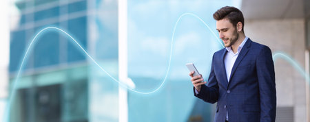 Smiling caucasian young guy businessman in suit typing on phone, has good deal near building office...