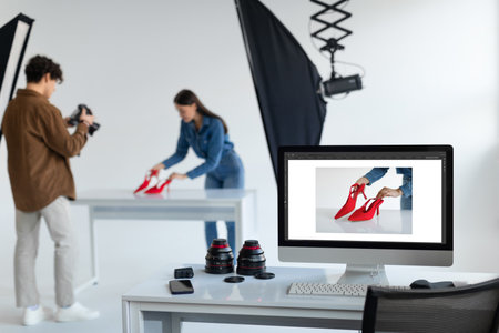 Team of professionals, photographer and his assistant working and taking photos of shoes in studio, focus on monitorの素材 [FY310201618063]