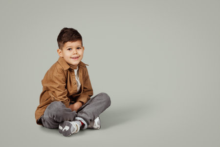 Cheerful caucasian 6 years old little boy in casual sit on floor with empty spaceの写真素材