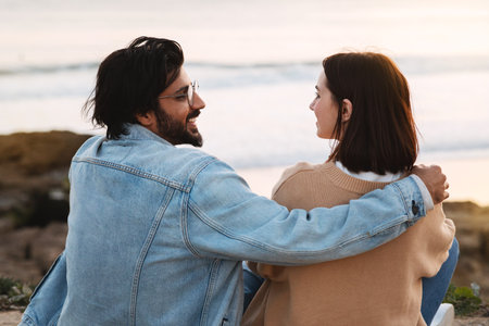 Happy young international guy and woman tourists in casual and glasses hugs, enjoy travel, date on beachの写真素材