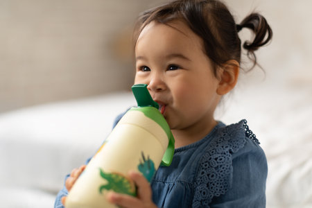Asian Infant Toddler Girl Drinking Water Holding Bottle At Homeの写真素材