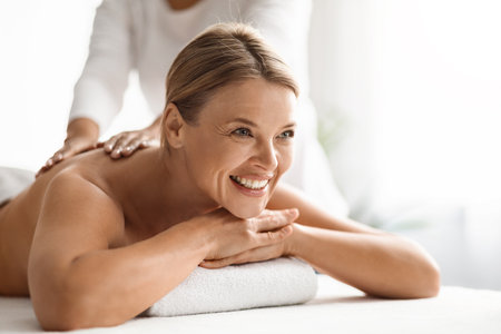 Portrait Of Beautiful Middle Aged Woman Having Back Massage In Spa Salonの写真素材