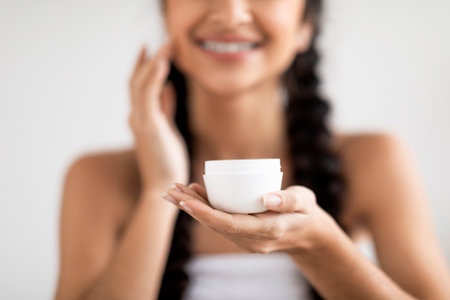 Skincare Product. Beautiful Young Indian Woman Holding Jar With Moisturising Creamの写真素材