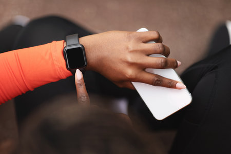 Millennial african american lady in sportswear check fit tracker, smart watch with empty screenの写真素材