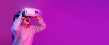 Amazed preteen girl experiencing VR headset game on colorful backgroundの写真素材